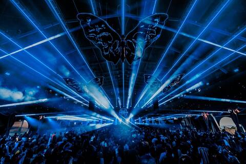 Crowd enjoying a laser-filled night at Tomorrowland’s Freedom Stage with butterfly light installation.