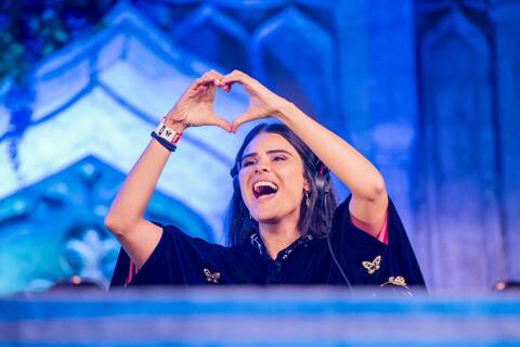 DJ ANNA performing on the Tomorrowland Brasil 2025 Mainstage, forming a heart symbol with her hands during her set.