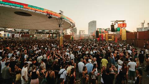 Large crowd gathered at Brunch Electronik’s main stage in Barcelona surrounded by colorful shipping containers and urban skyline