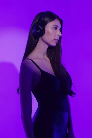 DJ Luane in profile wearing headphones against a purple lit background