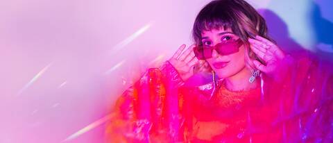 Electronic music DJ Elisa Amaral portrait with vibrant pink lighting and futuristic visual style